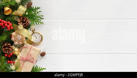 Rami di abete con orologio tascabile, decorazioni natalizie e scatola regalo su fondo in legno bianco Foto Stock