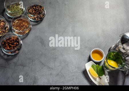 Layout creativo con tè, tè verde, tè nero e vari tipi di frutta e tisane su sfondo di pietra scura. Posa piana. Foto Stock