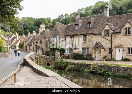 I pittoreschi cottage in pietra tradizionale accanto al ponte sul fiume Brook nel villaggio incontaminato di Cotswold di Castle Combe, Wiltshire, Inghilterra, Regno Unito Foto Stock