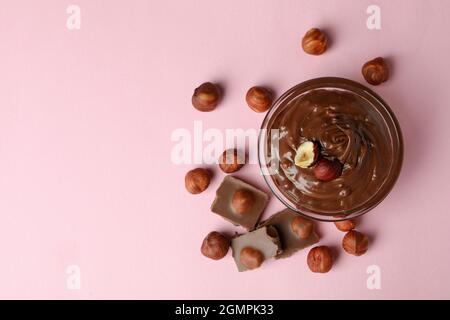 Ciotola con pasta di cioccolato, noci e cioccolato su sfondo rosa Foto Stock