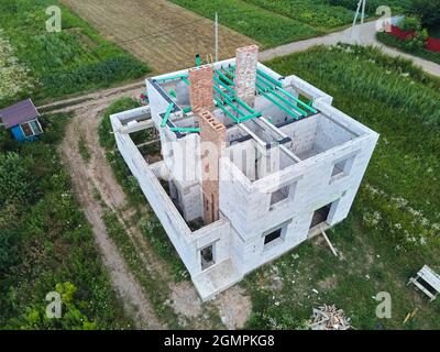 Vista aerea di telaio incompiuto di casa privata con pareti aerate in calcestruzzo leggero e travi in legno tetto in costruzione. Foto Stock