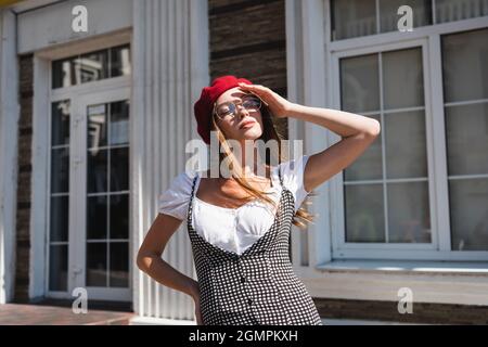 giovane donna in berretto rosso e occhiali che coprono il viso dal sole Foto Stock