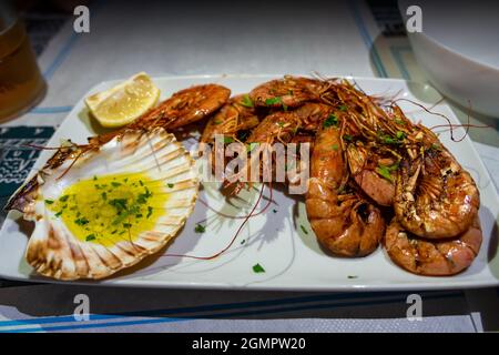 gamberi alla griglia con olio d'oliva aglio tuffo in una decorazione a guscio. Foto Stock