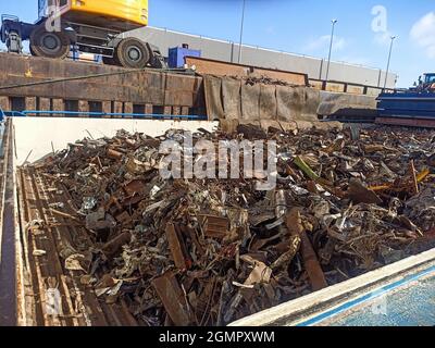 carico e scarico di rottami metallici nel porto sul molo dalla stiva della nave. Riutilizzo delle risorse. Esportazione di rifiuti metallici per il riciclaggio spedizione Foto Stock