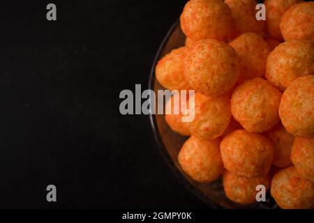 Spuntino al formaggio da una pentola di vetro con bastoncini di formaggio e palle di formaggio su un tavolo di legno nero Foto Stock