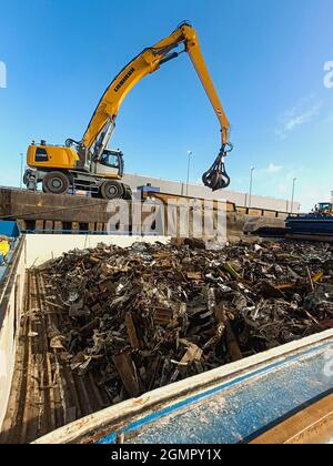 Riutilizzo delle risorse. Esportazione di rifiuti metallici per il riciclaggio spedizione via mare di rottami metallici. Carico e scarico di rottami metallici nel porto sul molo Foto Stock