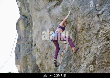 Immagine di sfocatura del movimento della giovane donna arrampicatrice che cade dopo il tentativo fallito di salire ripida parete di montagna rocciosa. Il concetto di sport estremi. Foto Stock