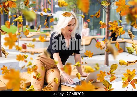 Donna carina con computer portatile nel parco autunnale Foto Stock