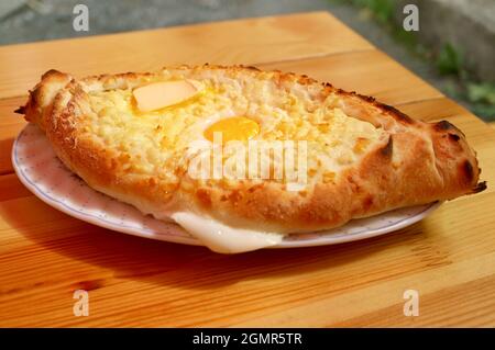 Adjaruli Khachapuri appena sfornato, formaggio tradizionale georgiano e pane all'uovo su tavola di legno Foto Stock