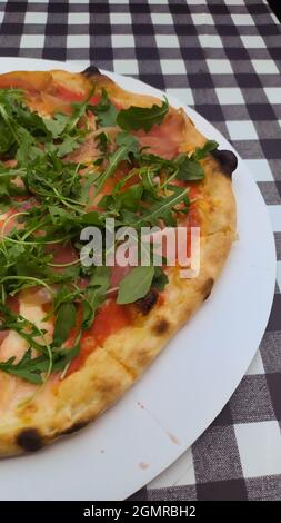 Pizza di prosciutto e rucola su sfondo quadrato bianco e nero Foto Stock