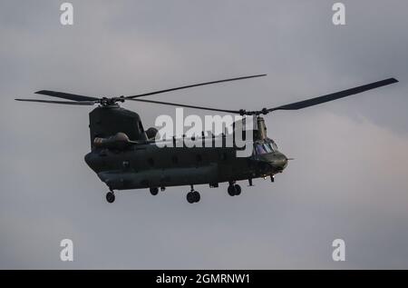 Elicottero CH-47 a rotore tandem RAF Chinook che vola veloce e basso in un cielo grigio blu nuvoloso in un esercizio di battaglia militare, Wilts UK Foto Stock