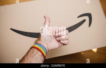 Approvazione mano segno indossare un bracciale gay con Amazon prime cartone sullo sfondo Foto Stock