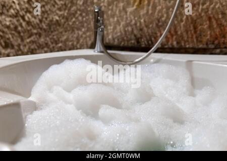 Jacuzzi, acqua schiumosa, pareti in pietra naturale e bagno d'epoca Foto Stock