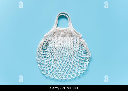 Borsa in mesh ecologica vuota bianca riutilizzabile su sfondo blu. Concetto senza plastica, senza sprechi e cura dell'ambiente. Spazio di copia Vista superiore Layout f Foto Stock