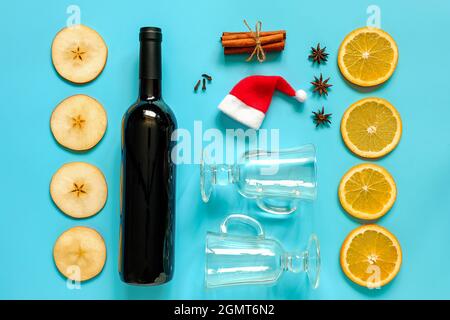 VIN brulé ingredienti, ancora vita su sfondo blu. Bottiglia di vino, bastoncini di cannella, fette di arancia, mela, anice e tazza. Concetto culinario reci Foto Stock