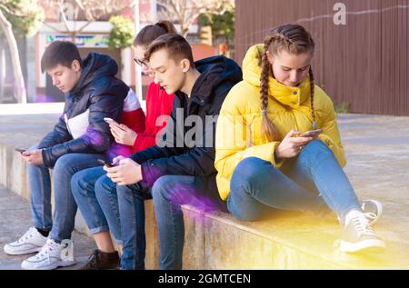 Adolescenti assorbiti in telefoni all'aperto Foto Stock