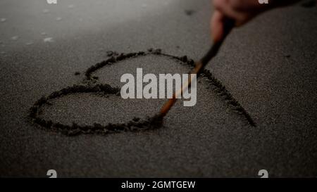 La persona attira un cuore sulla spiaggia, e poi l'onda cancella il cuore disegnato sulla spiaggia Foto Stock