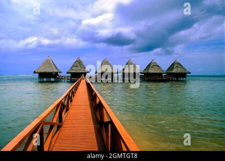 Tahiti, Polinesia Francese - Marzo 1984; Una linea di capanne sulla spiaggia di Moorea in Polinesia Francese fa un affascinante schema astratto Foto Stock