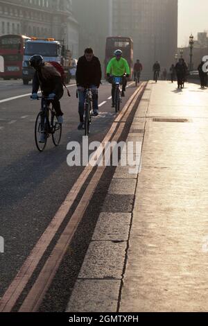 Londra, Inghilterra - 30 marzo 2012 i ciclisti, i pendolari e i pedoni della mattina presto attraversano Westminster Bridge, Londra, proprio come il sole sta aumentando. Foto Stock