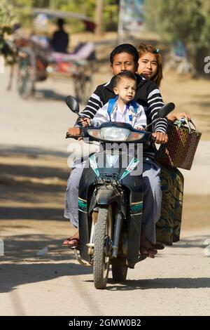 Bagan, Myanmar - 29 Gennaio 2013 scena quotidiana in una strada trafficata in Myanmar. Tre su un ciclomotore. Niente preoccupazioni. Che cosa potrebbe andare storto? Foto Stock