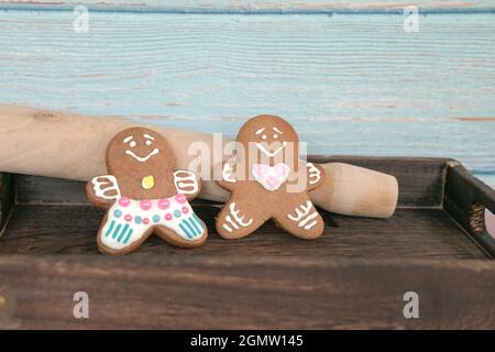I biscotti dell'uomo del pan di zenzero su un vassoio marrone appoggiano contro un perno di rotolamento Foto Stock