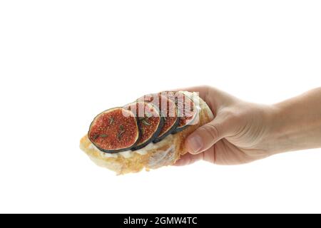 La mano femmina tiene la bruschetta con il fico, isolata su sfondo bianco Foto Stock