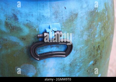 Fusto in plastica con manico nero, vista del manico del tamburo dal vecchio fusto di stoccaggio dell'acqua con crescita di funghi sulle parti esterne Foto Stock