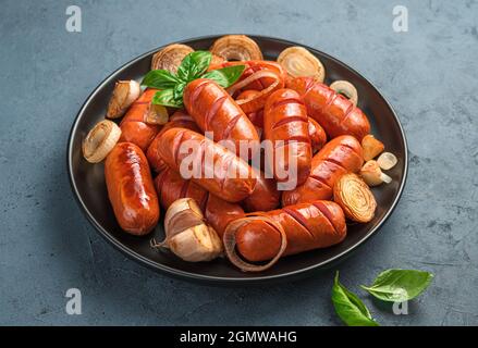 Salsicce fritte in un piatto nero su sfondo scuro. Vista laterale, primo piano. Foto Stock