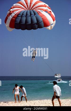 Pattaya, Thailandia - Octo ber 1984; la gente fa un sacco di cose strane sulle spiagge - presumibilmente per divertimento! Essere trainato su un paracadute dietro un motoscafo può Foto Stock