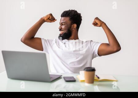 Felice AFRICAN-AMERICAN businessman in tuta guardando laptop eccitato da buone notizie on line, uomo nero vincitore seduto alla scrivania in ufficio obiettivo raggiunto uva passa Foto Stock