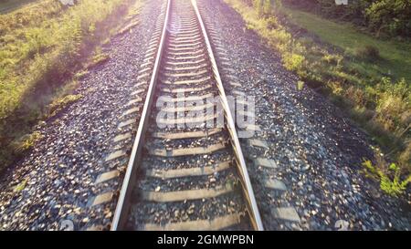 Luce solare e traffico sulla ferrovia. Il sole splende nell'obiettivo della fotocamera. Foto Stock