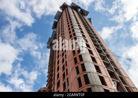 costruzione di un alto edificio residenziale a più piani in città il giorno d'estate Foto Stock
