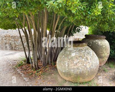 Catania, Sicilia, Italia - 22 settembre 2019 massicce pentole di pietra e un vecchio muro in un giardino all'esterno di un'antica villa vicino a Catania sulla costa orientale della Sicilia Foto Stock