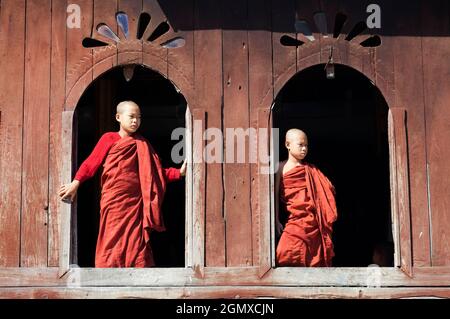 Lago Inle, Myanmar - 1 febbraio 2013; un biy in shot. Due giovani monaci tirocinanti accanto alla finestra in questo bellissimo monastero costruito in teak vicino al lago panoramico in Foto Stock
