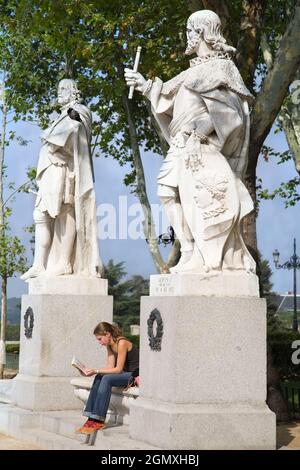 Madrid, Spagna - 23 settembre 2008; una donna in vista. Sta leggendo un libro cartaceo mentre è racchiuso tra due statue reali nel parco pubblico outsid Foto Stock