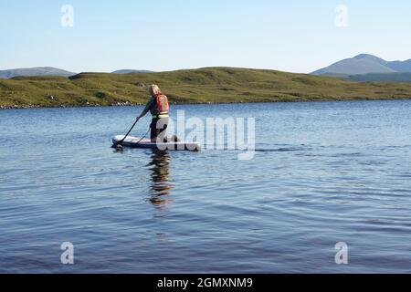 Signora più anziana che usa stand up paddle board Loch Laidon, Highlands scozzesi Foto Stock