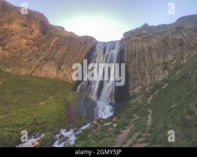 Una bella cascata in montagna. L'acqua dolce scende dal ghiacciaio. Tramonto in montagna. Foto Stock