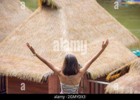 L'immagine dietro le donne alzano le braccia guardate la zattera di legno sull'acqua al Resort Wangnokkaew Park View Kanchanaburi , Thailandia Foto Stock