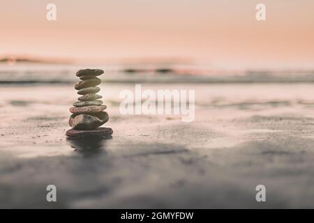 pietre equilibrate sulla riva della spiaggia per meditare e cercare l'equilibrio Foto Stock
