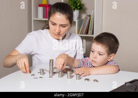 Madre e bambino imparano l'alfabetizzazione finanziaria per i bambini, per investire. Denaro, monete, crescita del reddito e acquisto di azioni. Foto Stock