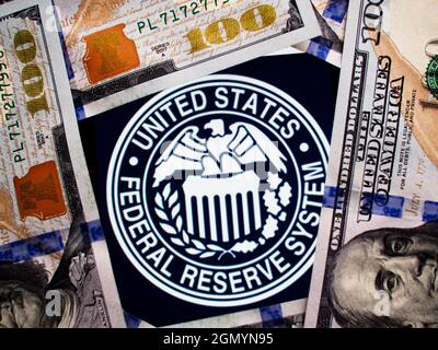 In questa foto raffigura il sigillo della Federal Reserve visualizzato su uno smartphone sullo sfondo delle banconote in dollari statunitensi Foto Stock
