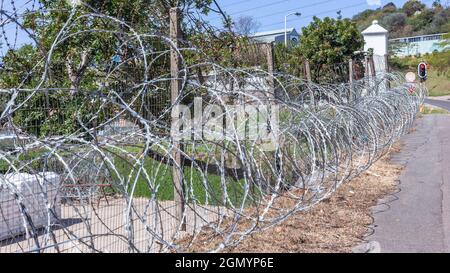 Filo di rasoio installato sulla recinzione di confine della fabbrica per la protezione dei prodotti fabbricati da furto dalla strada. Foto Stock