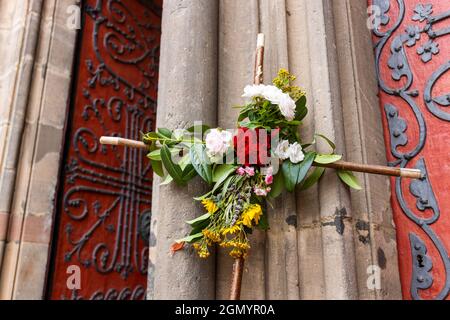 La croce del pellegrino in legno decorata con fiori si affaccia sul portale principale della Chiesa di Santa Elisabetta a Marburg, in Germania, un'importante meta di pellegrinaggio Foto Stock