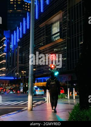 JAKAR, INDONESIA - 07 luglio 2021: Una persona che cammina di notte di fronte ai grattacieli nell'area finanziaria SCBD di Jakarta Indonesia Foto Stock