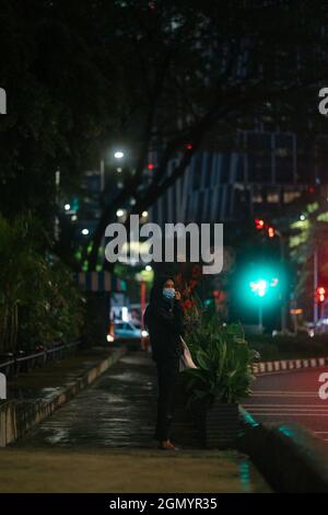 JAKAR, INDONESIA - 07 luglio 2021: Una persona che cammina di notte di fronte ai grattacieli nell'area finanziaria SCBD di Jakarta Indonesia Foto Stock