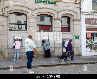 Truro, Regno Unito, 21 settembre 2021, Signore che usano l'ATM alla Lloyds Bank a Truro, Cornovaglia come la gente cammina passato. La cattedrale sembrava stupefacente sotto il cielo blu. Le previsioni sono per 19C, intervalli di sole e una brezza moderata.Credit: Keith Larby/Alamy Live News Foto Stock