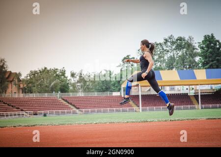 Giovane atletica si allunga e si prepara a correre. Donna sportiva forte Foto Stock