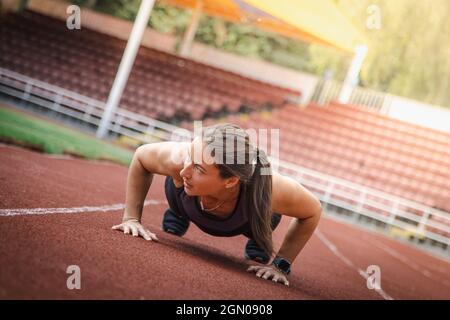 Giovane atletica si allunga e si prepara a correre. Donna sportiva forte Foto Stock