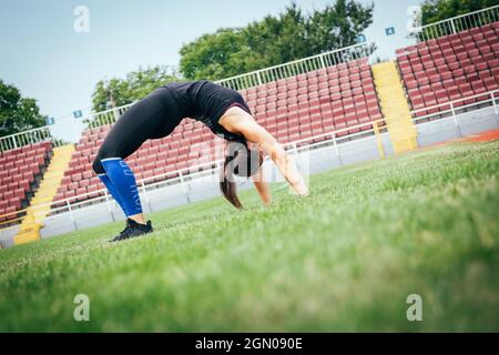 Giovane atletica si allunga e si prepara a correre. Donna sportiva forte Foto Stock