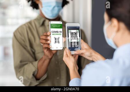 Nuovo normale. Female Worker Scanning QR Code, controllo del certificato di vaccinazione digitale del cliente Foto Stock